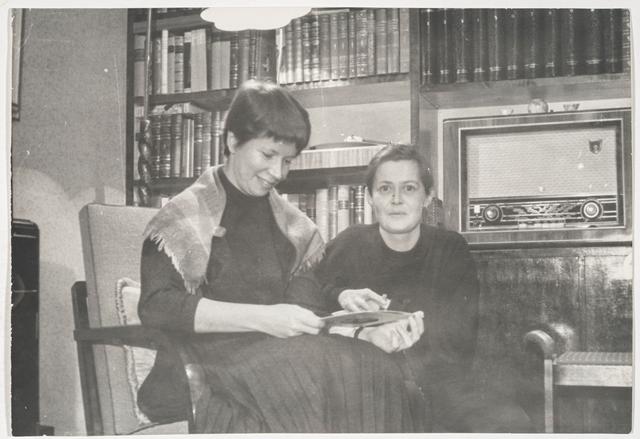 Mustavalkoisessa 1955 valokuvassa lyhyttukkaiset Sirkka Meriluoto ja Helvi Juvonen istuvat tutkimassa kuva-albumia.